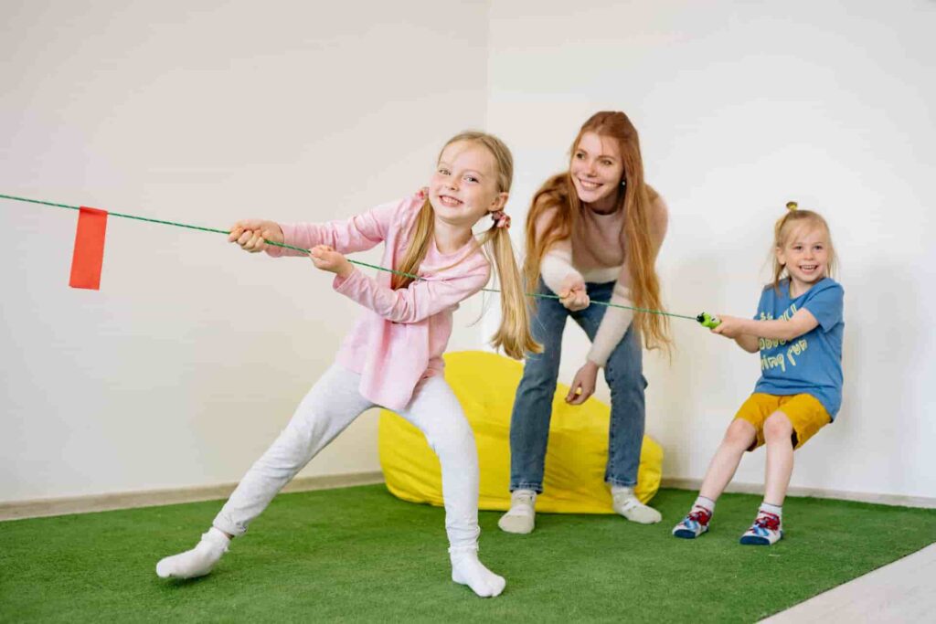 Children playing tug-of-war indoors as part of gym games for preschoolers, emphasizing teamwork and fun physical activity.