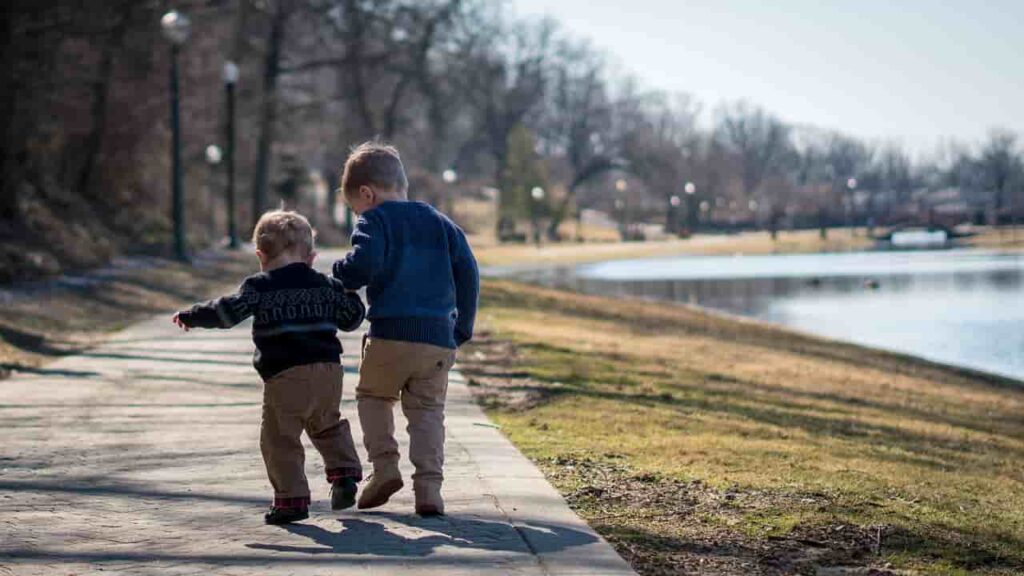 two young boys walking on a sidewalk