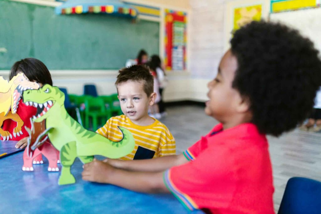 a group of children playing with a paper dinosaur