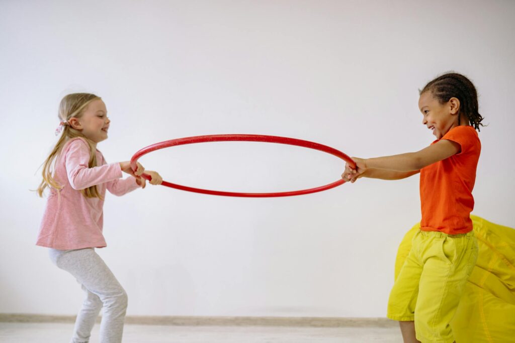 A group of kids playing with a hula hoop, enjoying aerobics for preschoolers